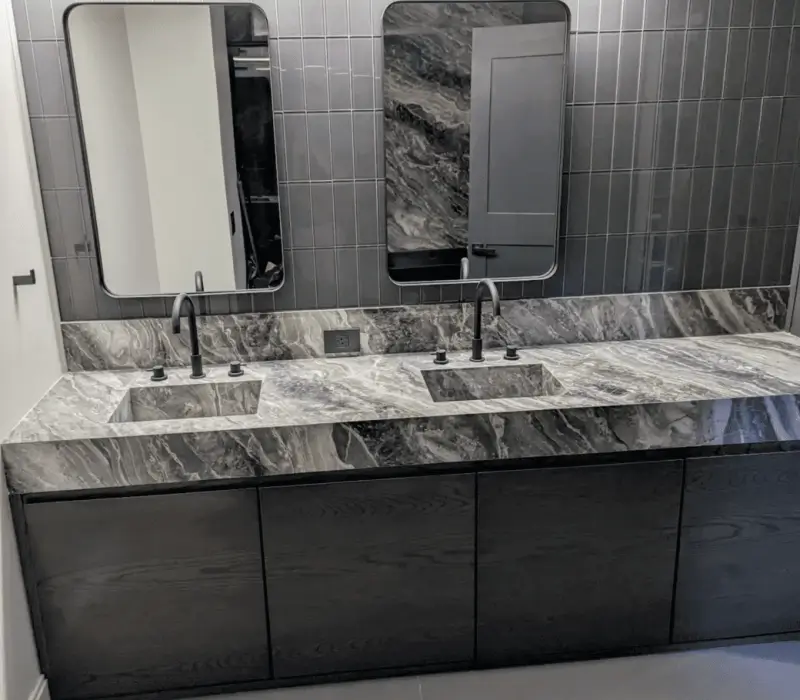 Modern bathroom with double sinks and dark cabinets.