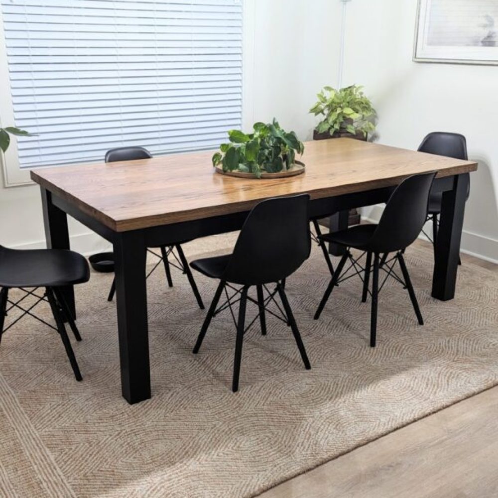 Dining room table with black chairs and rug.